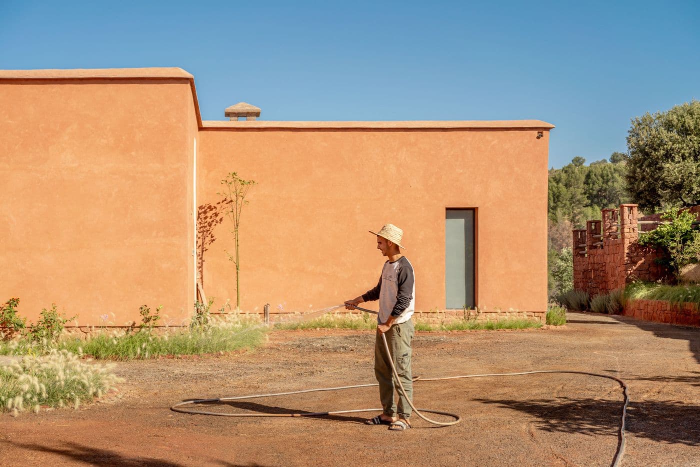 Jardinier en plein arrosage devant la façade du Domaine Eladâr