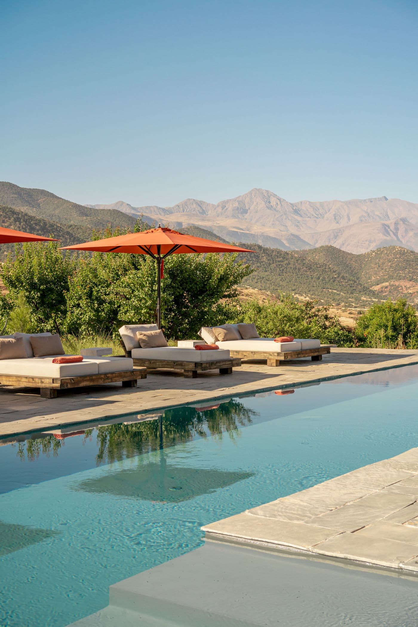 Piscine, transats et parasols avec vue sur l’Atlas, cadrage vertical au Domaine Eladâr