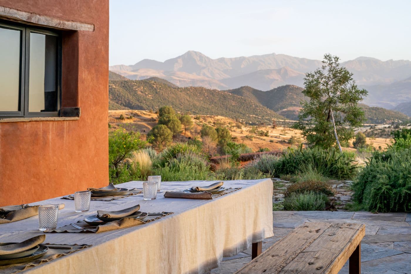 Table de repas devant la façade en pisé avec vue sur l’Atlas au Domaine Eladâr